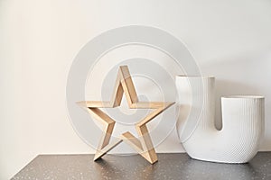 Part of the interior, a designer white vase and a wooden star on the table. Template for your product. Copy space.