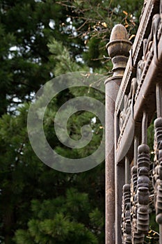 Part of the iron-gates curtained against the background of green trees. Architecture.