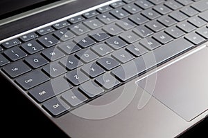 Part of laptop keyboard and touchpad of opened laptop isolated on black side view