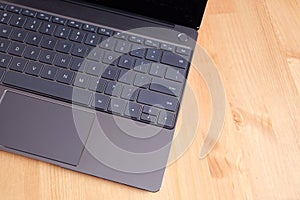 Part of laptop keyboard and touchpad of opened laptop on wooden table top view