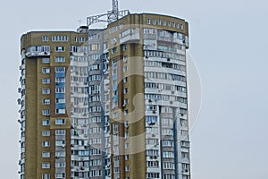 Part of a large multi-storey building with windows and balconies against a gray sky