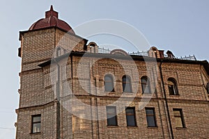 Part of a large old brown brick house with a row of windows with one large tower