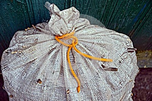 Part of a large old gray bag tied with an orange lace