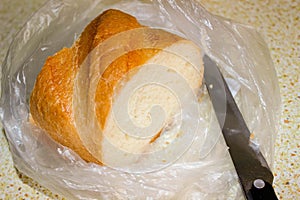 Part of a loaf in a cellophane bag with a knife next to it