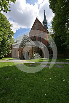 Part of the Luebeck cathedral with narthex and ridge turret, view from the idyllic churchyard with  lawn and old trees, copy space