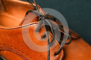 Part of men`s shoes close-up. Focus on the black laces. Men`s shoes made of genuine leather. Brown shoes