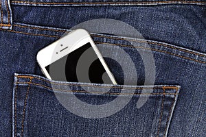 Part of mobile white cellphone in the back pocket of blue denim