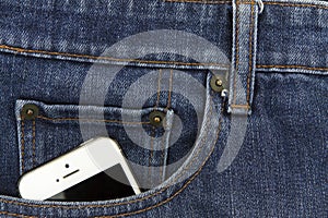 Part of mobile white cellphone in the front pocket of blue denim