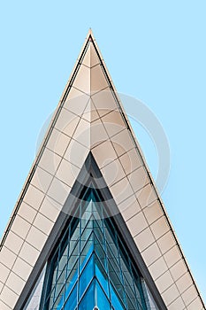 Part of modern office building with glass facade against blue sky, low angle view, crop. Skyscraper in the city center