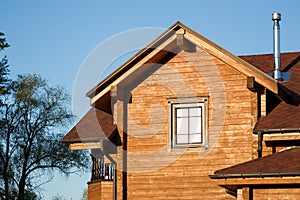 Part of modern wooden country house with blue sky on background. Roof of eco residential building near forest. Building