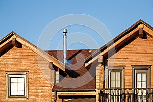 Part of modern wooden country house with blue sky on background. Roof of eco residential building near forest. Building