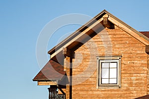 Part of modern wooden country house with blue sky on background. Roof of eco residential building near forest. Building and archit