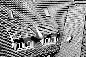 Part of a newly covered house roof with dormer windows and roof hatches in b & w