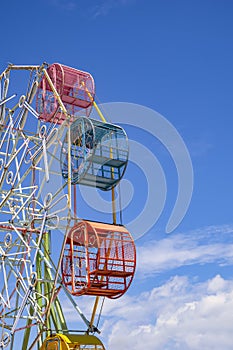 Part of the old colorful Ferris wheel with fluorescent lamp decoration against cloud on blue sky background in vertical frame