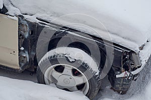 Part of an old disassembled car in the snow.