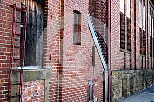 Part of an old factory with brick wall and window and a bent ladder,