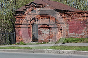 Part of an old red brick building with rusty metal roof