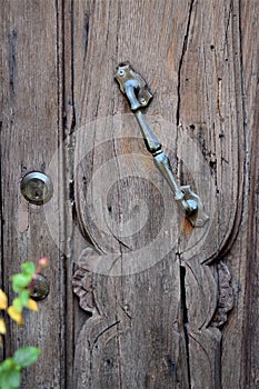 Part of an old wooden door and metal handle of a Barga tavern in the province of Lucca in Tuscany.