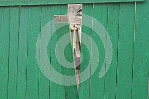 Part of an old wooden green fence wall with a broken plank