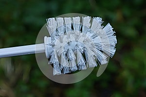 Part one of a plastic white toilet brush with plastic bristles