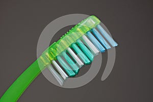 Part of one toothbrush with colored bristles on a green plastic handle