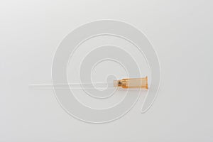 Part of orange intravenous cannula 14 G on white background, external diameter 2,1 mm, used in trauma, blood transfusion, surgery