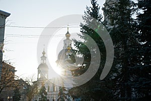 Part of ortodox church in front view with sun behind the clounds. The sun rays breaks through the dome of the church. Cross of