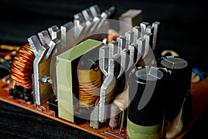 Part of pc power supply with radiator and electronic board with integrated stabilizers and filter capacitor with coils.