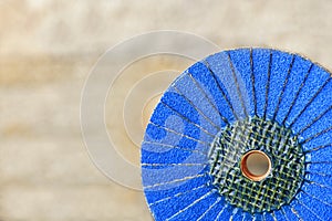 Flap grinding wheel blue on wood and metal on a light beige background in unsharp photo