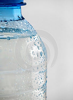 A part of a plastic bottle with clean water is visible on a white background.