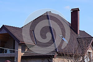 Part of a private house under a brown tiled roof with a window and a brick chimney