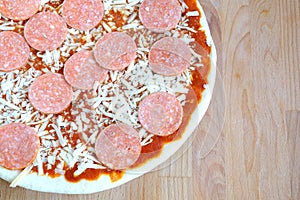 Part of raw pizza on brown kitchen table top view closeup photo