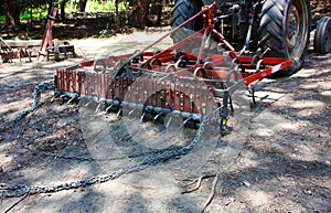 Part of a red combine harvester on a dusty ground