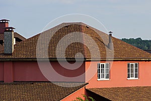 Part of a red house with windows with a brown tiled roof