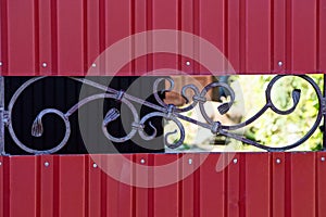 Part of red metal fence with forged pattern