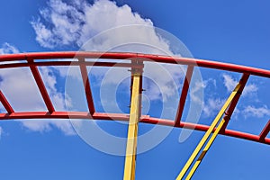 Part of a roller coaster. Background of blue sky and white clouds.