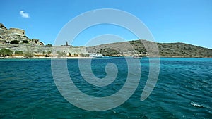 Part of the ruined fortress wall on the background of the sea and the mountains on the island of Spinalonga. Crete