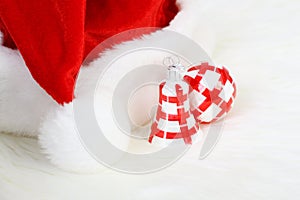 Part of Santa Claus hat with pom-pom and red and white Christmas ball and Christmas smaller bell on white fur