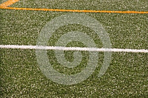 Part of sport soccer stadium and artificial turf football field. Detail, close up of green grass with white lines, goal line.