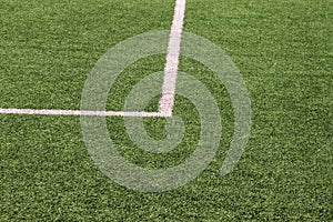 Part of sport soccer stadium and artificial turf football field. Detail, close up of green grass with white lines, goal line.