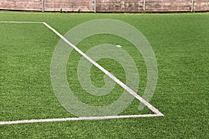 Part of sport soccer stadium and artificial turf football field. Detail, close up of green grass with white lines, goal line.