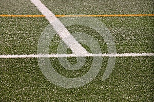 Part of sport soccer stadium and artificial turf football field. Detail, close up of green grass with white lines, goal line.