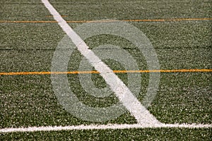 Part of sport soccer stadium and artificial turf football field. Detail, close up of green grass with white lines, goal line.