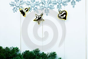 Part of spruce Christmas tree and golden ornaments and snowflakes on white wood background