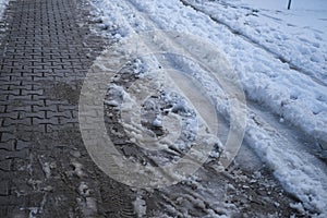 Part of street in city, pavement after heavy snowfall, wet snow melts, puddles, slush and mud impede movement of pedestrians and