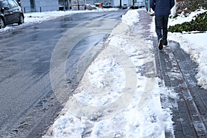 Part of street in city, pavement after heavy snowfall, wet snow melts, puddles, slush and mud impede movement of pedestrians and
