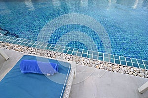 Part of Sun Bed and blue towel with copy space on top of swimming pool