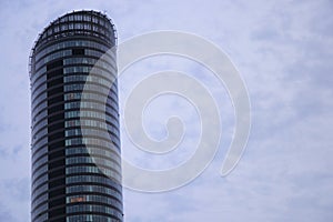 Part of a tall, glassy, modern skyscraper against the sky, with copy space