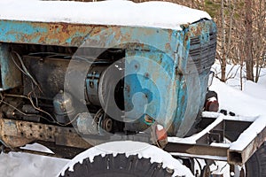 Part of the tractor in the yard of a rural house, close-up. Old tractor in the village in winter