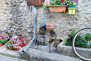 Part of typical provence house with drain pipe, flowers and bicycle